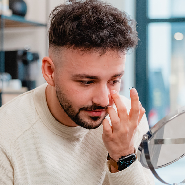 Un homme essayant de mettre une lentille de contact